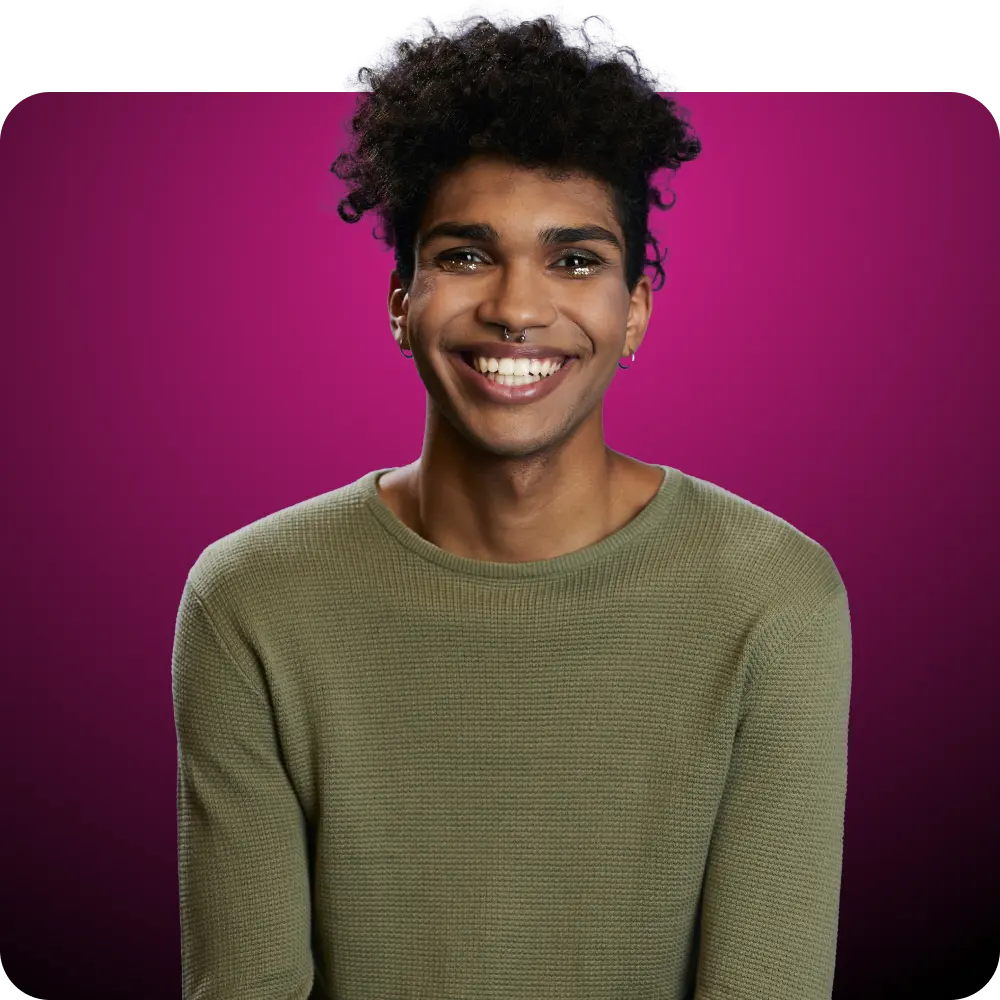 A smiling Q Care patient with a nose ring wearing a green sweater